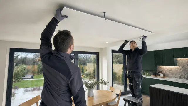 UK infrared heating installers mounting a ceiling panel in a British kitchen